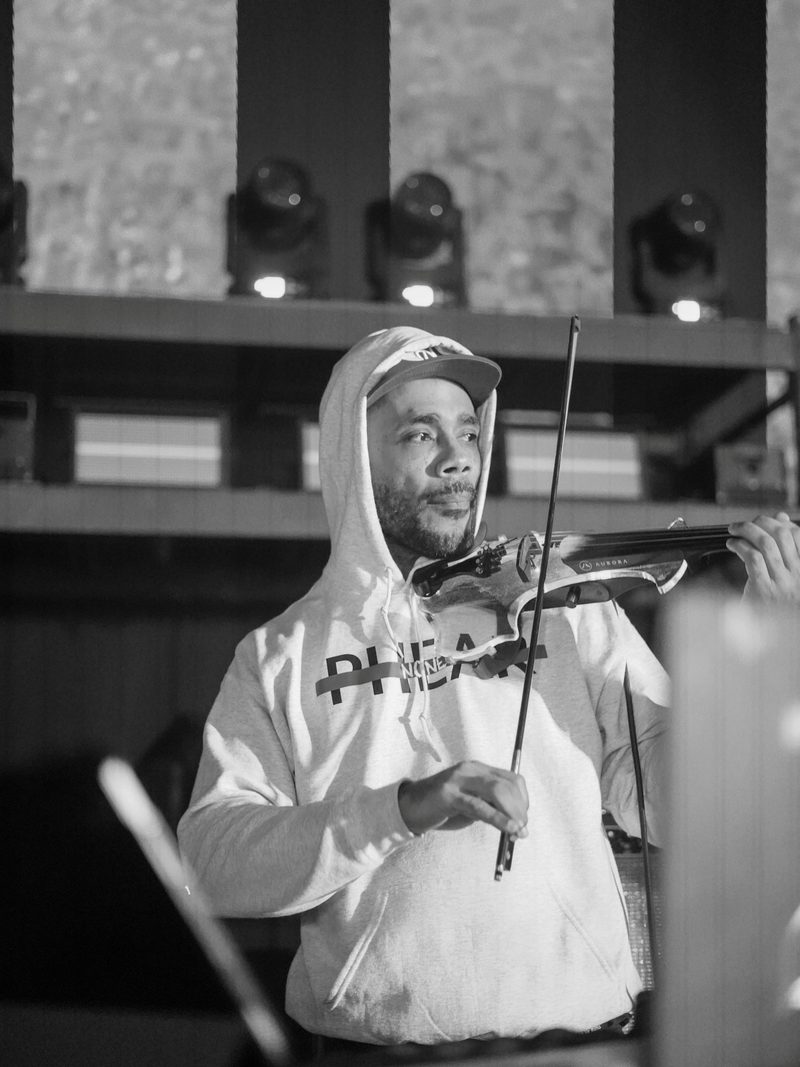 Opening violinist performing under stage lights before GZA's set, black and white concert photography