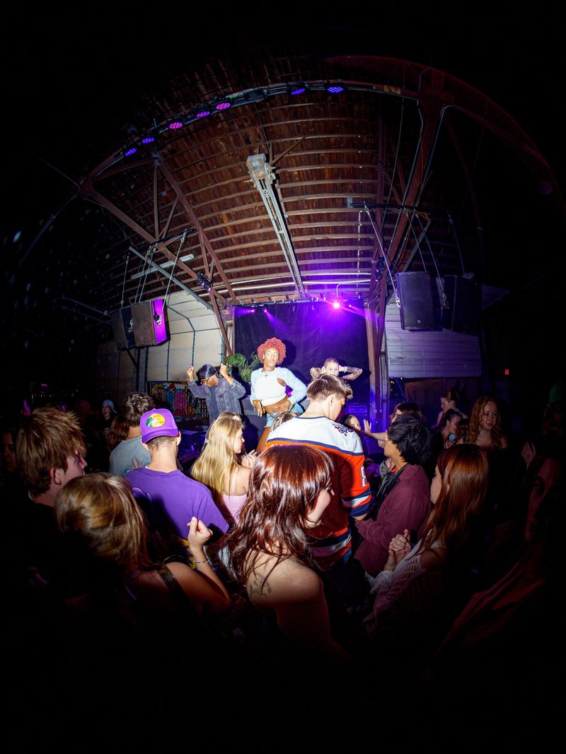 Fisheye crowd shot of dancers in Y2K outfits at a packed brewery party