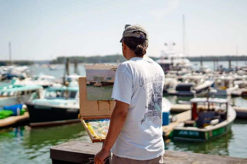 Plein air painter working an easel at a crowded Maine marina