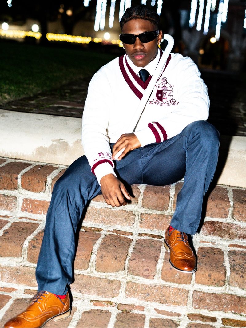 Fraternity member posed on brick steps at night with flash lighting