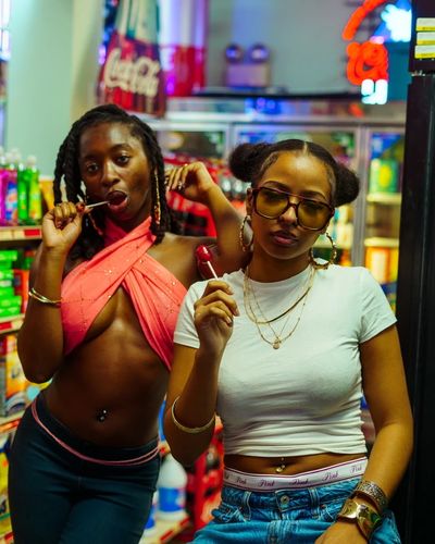 Two models posing under neon signage during an editorial photoshoot