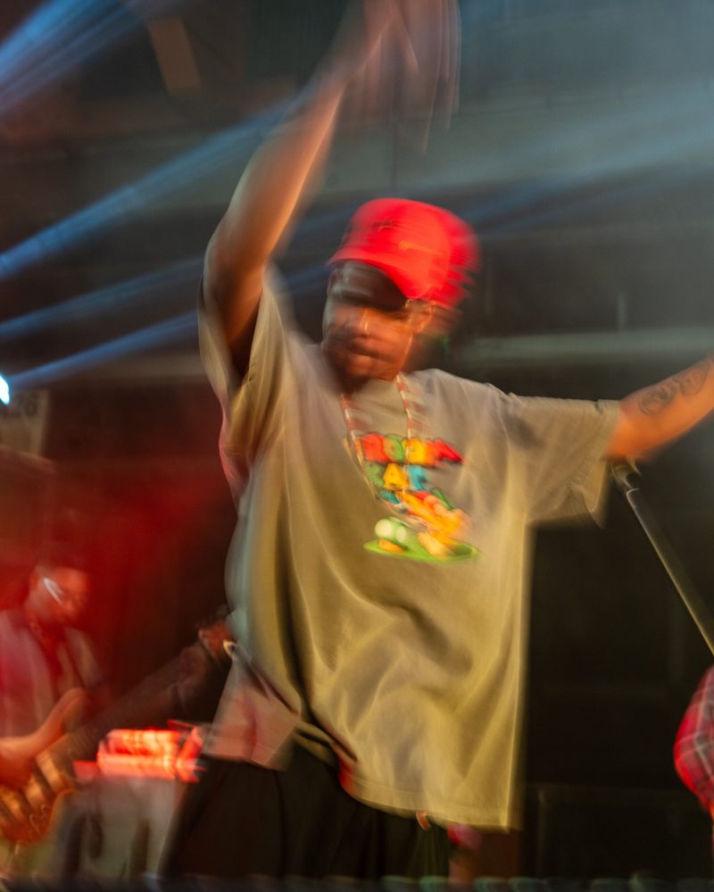 Dancer mid-movement with blurred arms and a sharp flash-frozen face on a nightlife dance floor